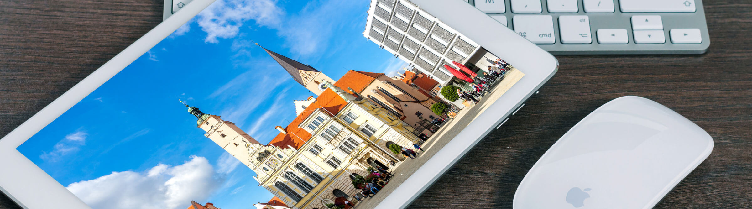 Header Bild von Ingolstadt auf einem Tablet, das auf einem Holzschreibtisch auf einer Tastatur und neben einer Maus liegt