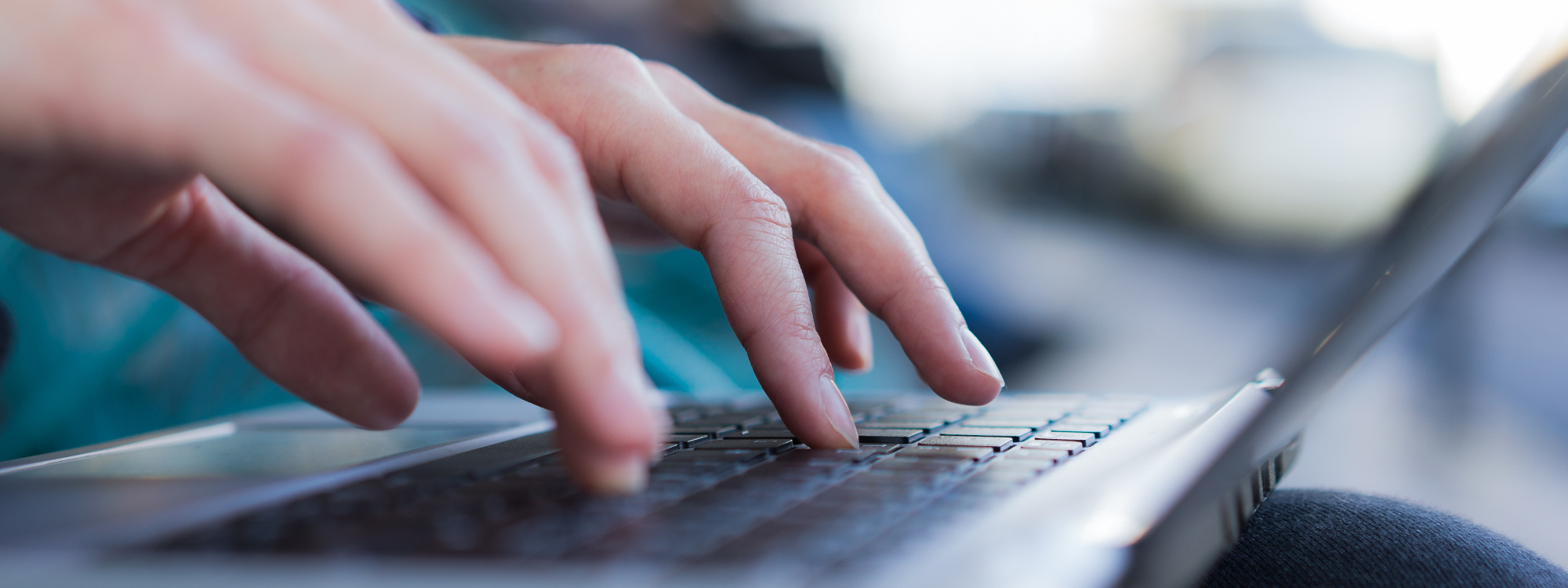 Person schreibt mit zehn Fingern auf einer Laptoptastatur